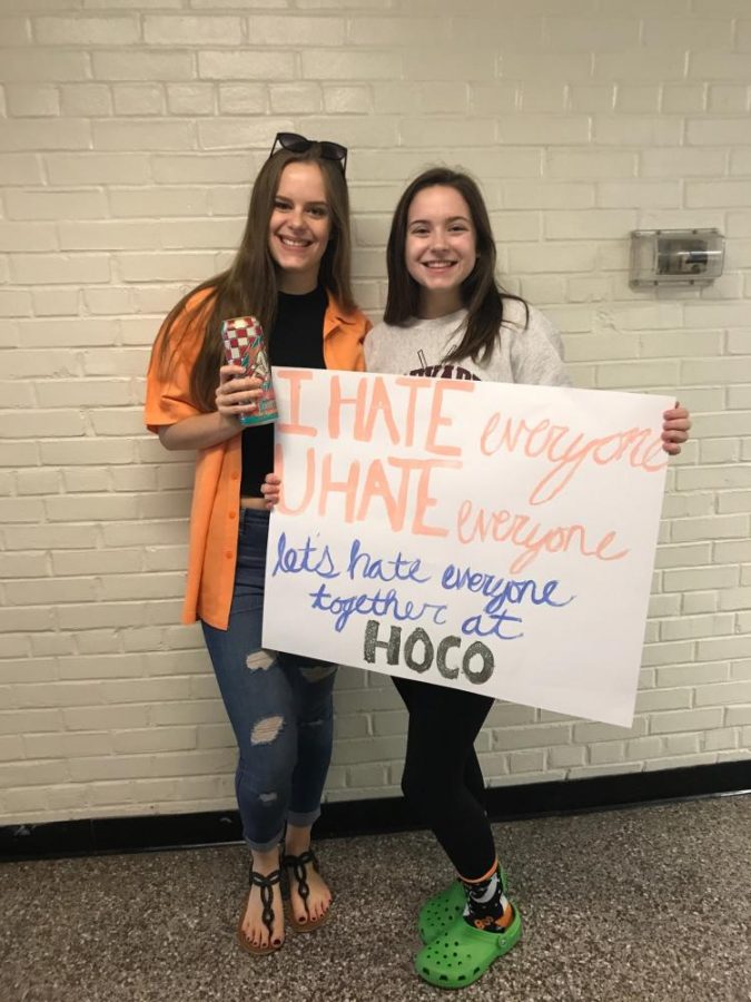 Seniors Nicole Mcmenomay and Anna Pearce pose with a homecoming proposal poster.