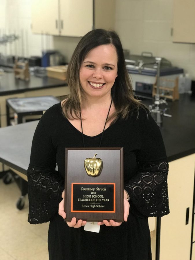 Courtney Struck, Utica High’s 2019 Teacher of the Year, poses with he plaque she was presented during class.. TOM LIETZ PHOTO