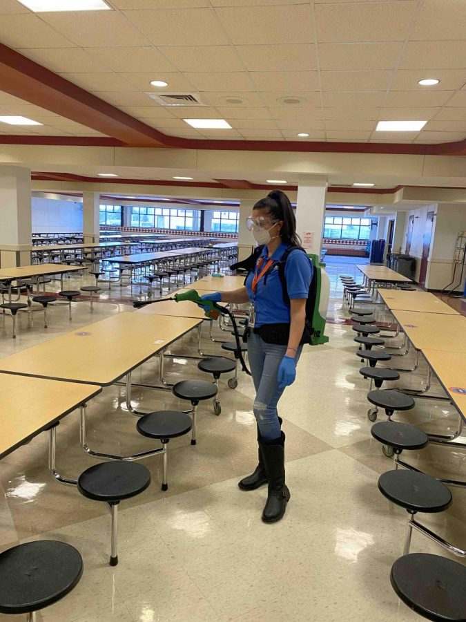 Custodian Liliana Djonovic wearing a Victory Electric Static Sprayer, using it to disinfect surfaces that are hard to get to.