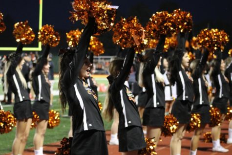 The sideline cheer team hypes up the crowd on the homecoming night. 