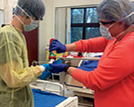 Wearing personal protective 
equipment, teacher
Melissa Rice squirts red paint (to simulate 
blood) onto senior Adam Stroup’s gloved 
hand. Students had to smear the paint 
around and remove their gloves without 
getting any “blood” on their skin.