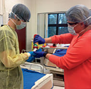 Wearing personal protective 
equipment, teacher
Melissa Rice squirts red paint (to simulate 
blood) onto senior Adam Stroup’s gloved 
hand. Students had to smear the paint 
around and remove their gloves without 
getting any “blood” on their skin.