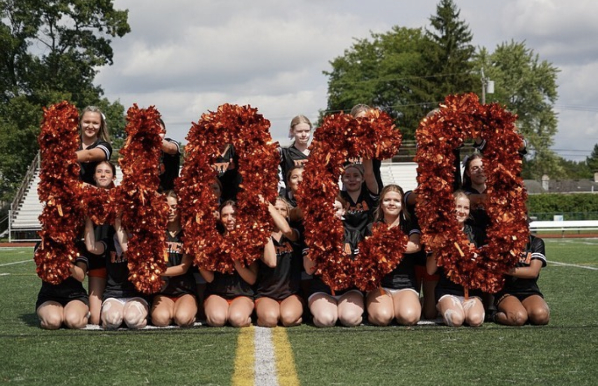 Cheerleaders hold up homecoming pompoms at the competition day.