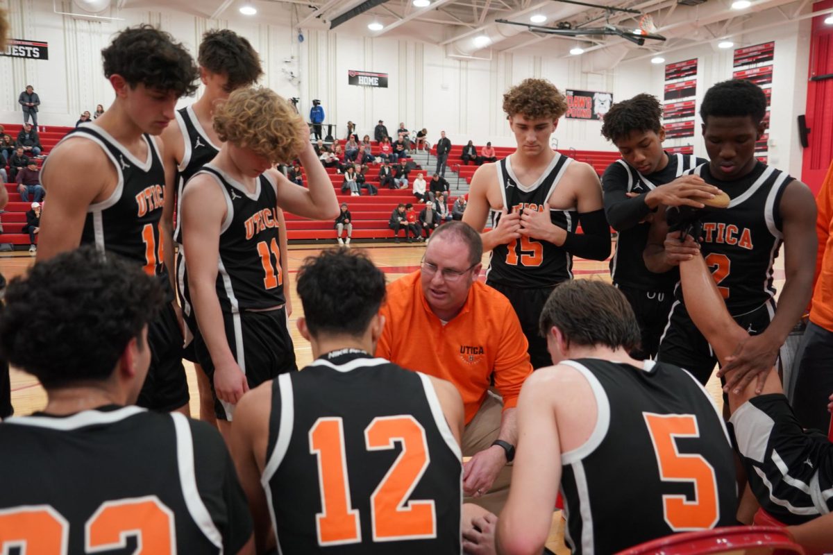 From the sidelines, coach Dave Hinkle discusses the next play with the varsity basketball team.