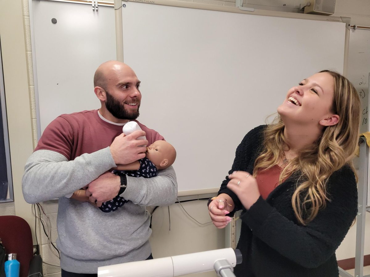 Sophomore Emma Mcintosh hands over her baby to teacher Michael Zalewski during U.S. History.