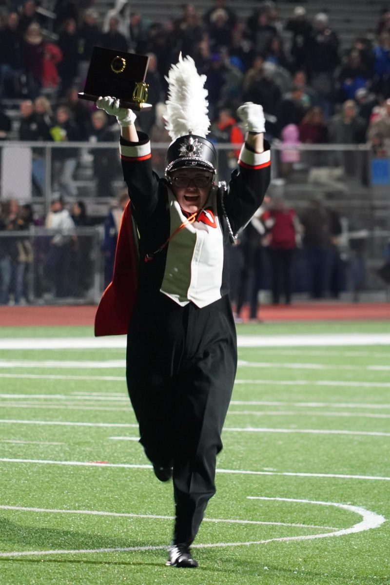 Senior Maia Suggs runs back to the band with their division 1 trophy from MSBOA festival. 