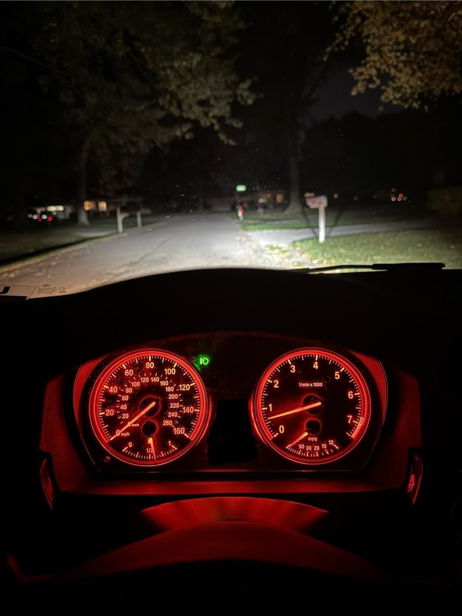 A cars dashboard with the headlights on revealing the night