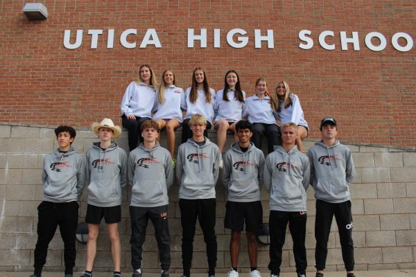 Girls and Boys cross country teams that qualified for states posing in front of Utica High School