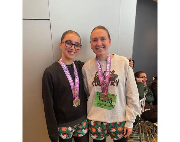 Junior Kara Boice and senior Vanessa Skorski take a picture with their medals from the Stuffing Strut 5k in Detroit. 