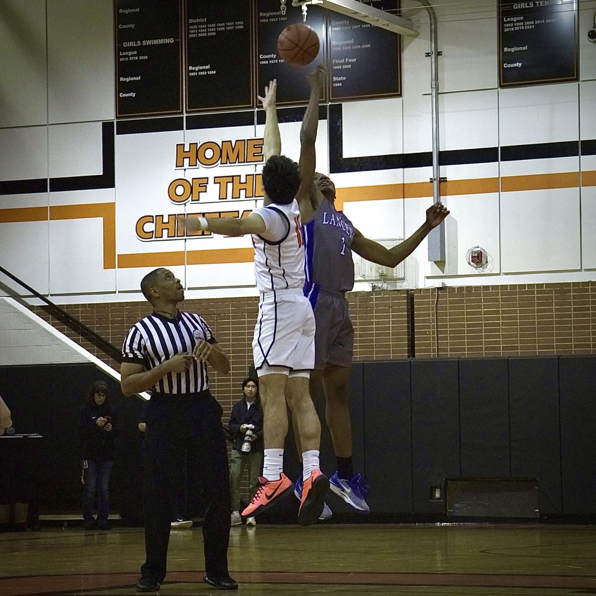 Photo of the Day #76!
Junior Hayden Hirmiz leaps into the air to achieve a successful "Jump Ball" against L'Anse Creuse to gain possession of the ball before passing it to his teammates.