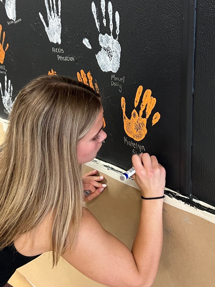 Senior Katelyn Stogrin signs her name underneath her handprint on the wall.  